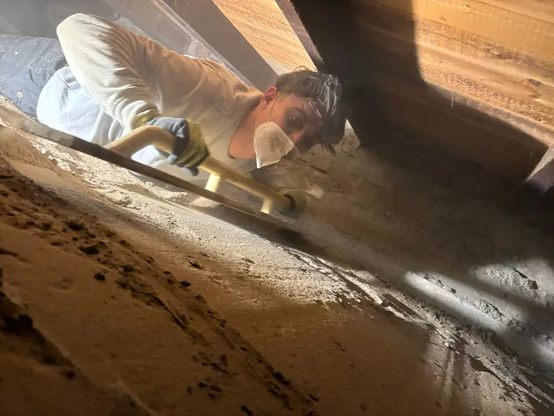 Medewerker van PuinVrij werkt met een mondkapje op liggend in een lage kruipruimte